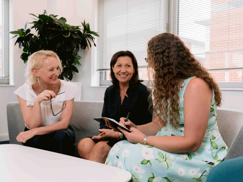 Three female colleagues in M&A sharing insights with empathy and connection