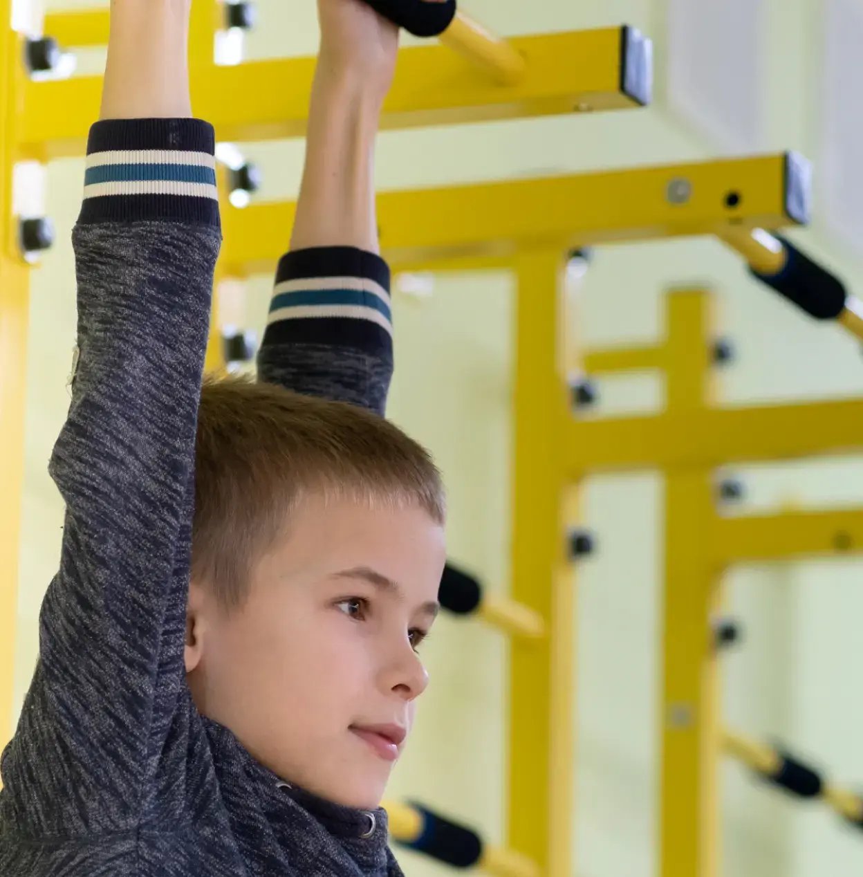 child hanging on gymnasium equipment