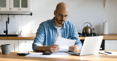 British SME founder sitting at a kitchen table reviewing funding documents in natural light