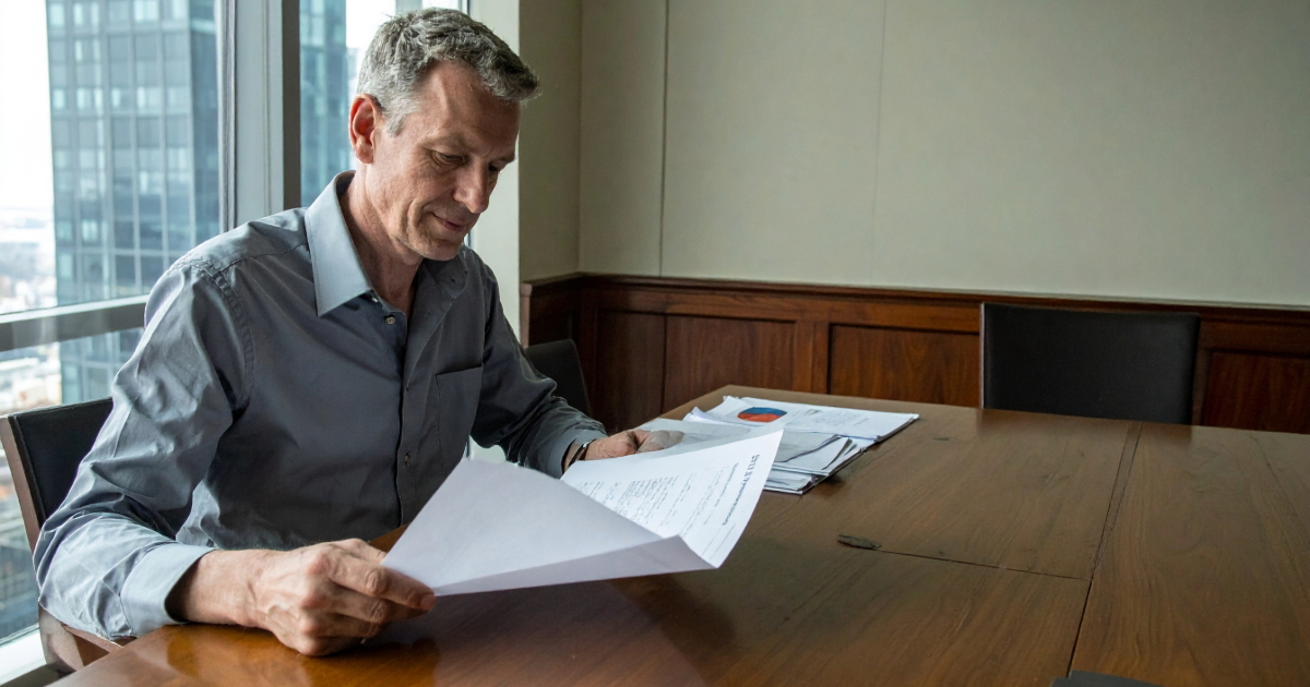 Senior executive reviewing acquisition target documents at a desk, natural daylight, documentary photojournalism aesthetic — CapEQ insights