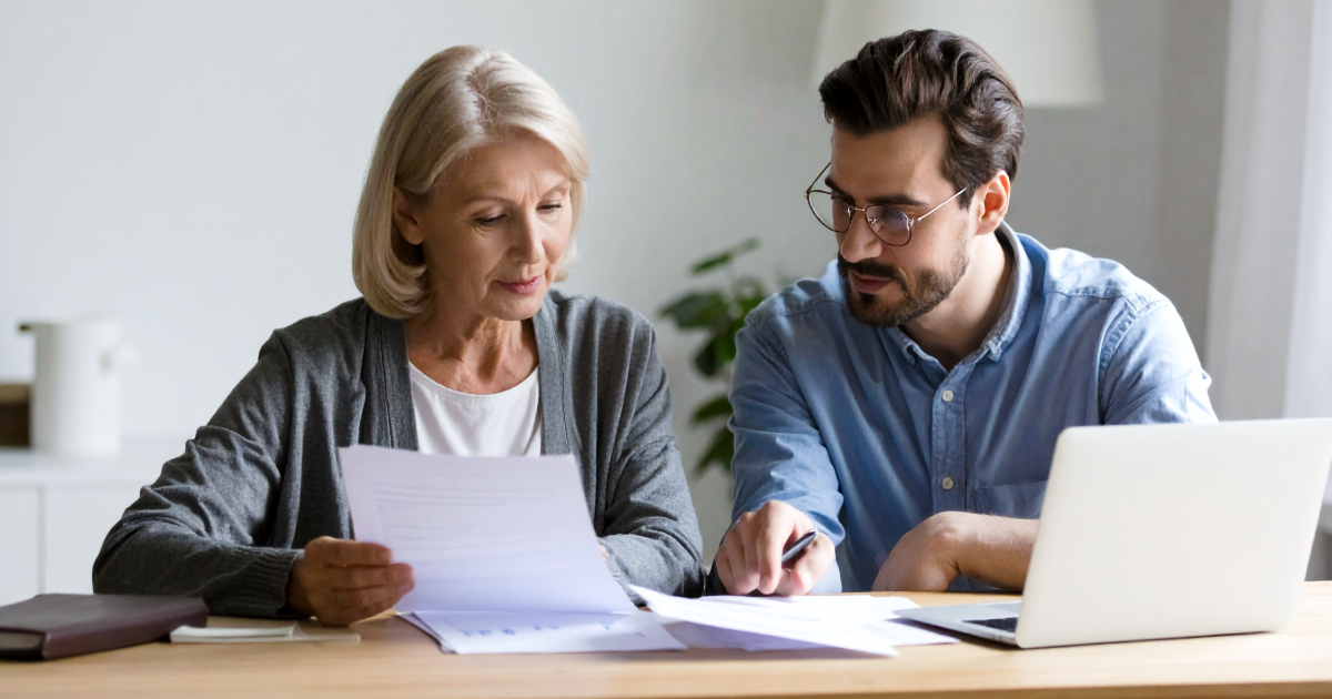 A business owner and adviser reviewing management accounts together at a table in natural light.