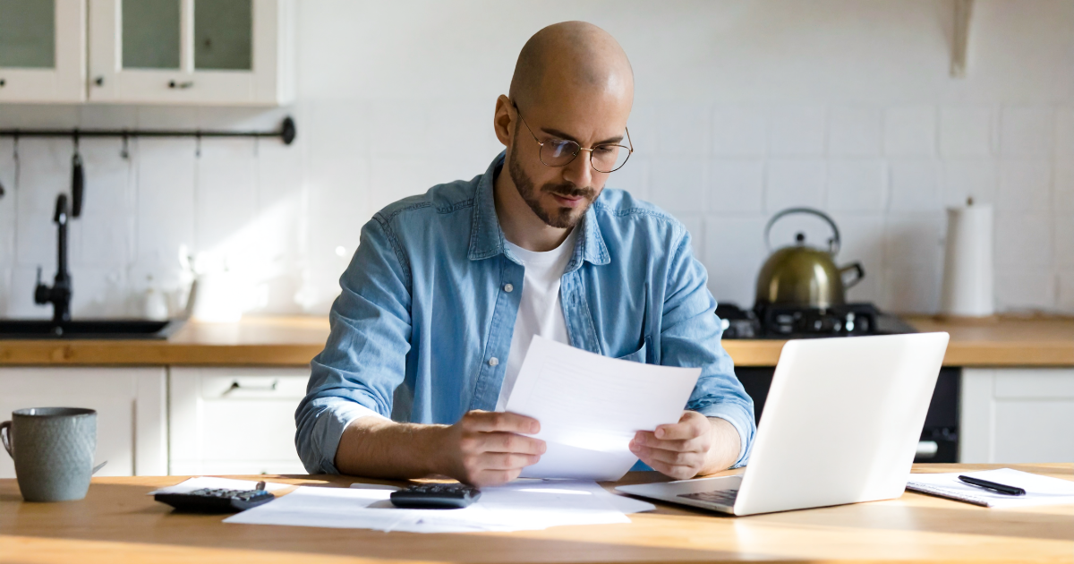 British SME founder sitting at a kitchen table reviewing funding documents in natural light